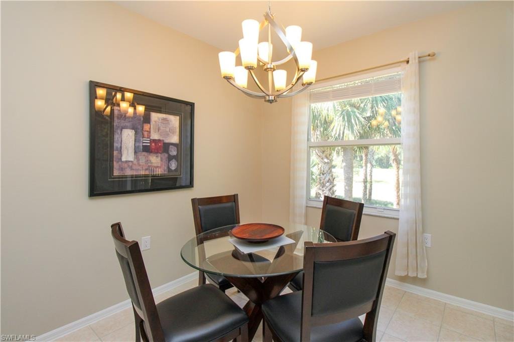 Dining area with light tile patterned floors and an inviting chandelier
