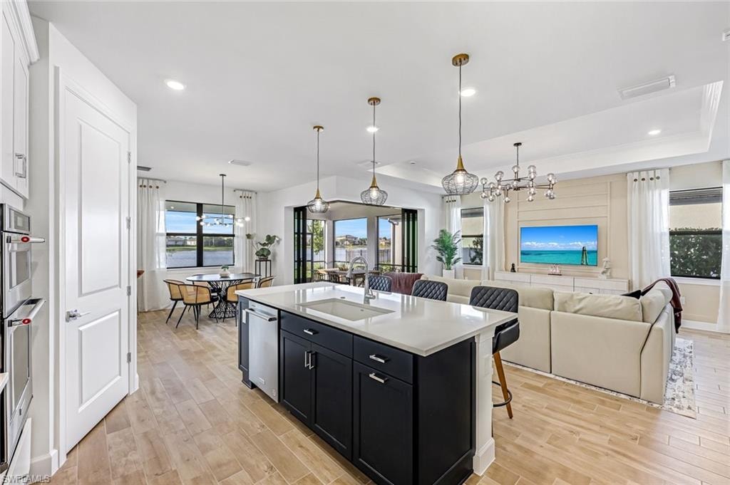 Kitchen featuring dark cabinetry, a kitchen breakfast bar, pendant lighting, light wood-style flooring, and recessed lighting