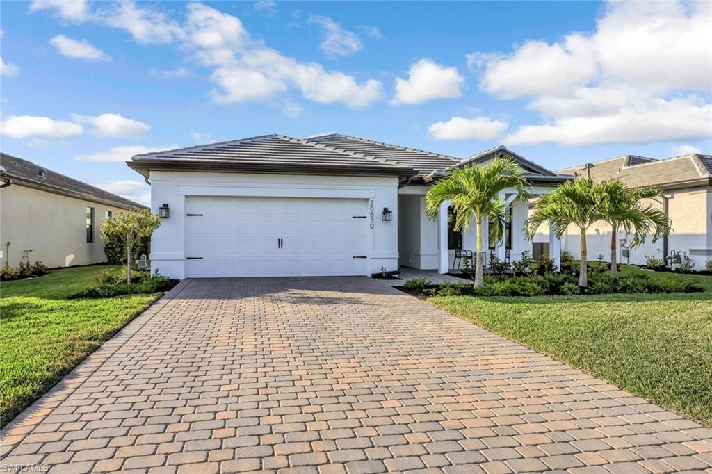 Ranch-style house with a front yard, stucco siding, and decorative driveway