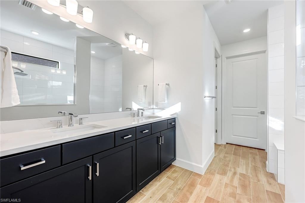 Bathroom featuring double vanity, wood tiled floors, and a tile shower