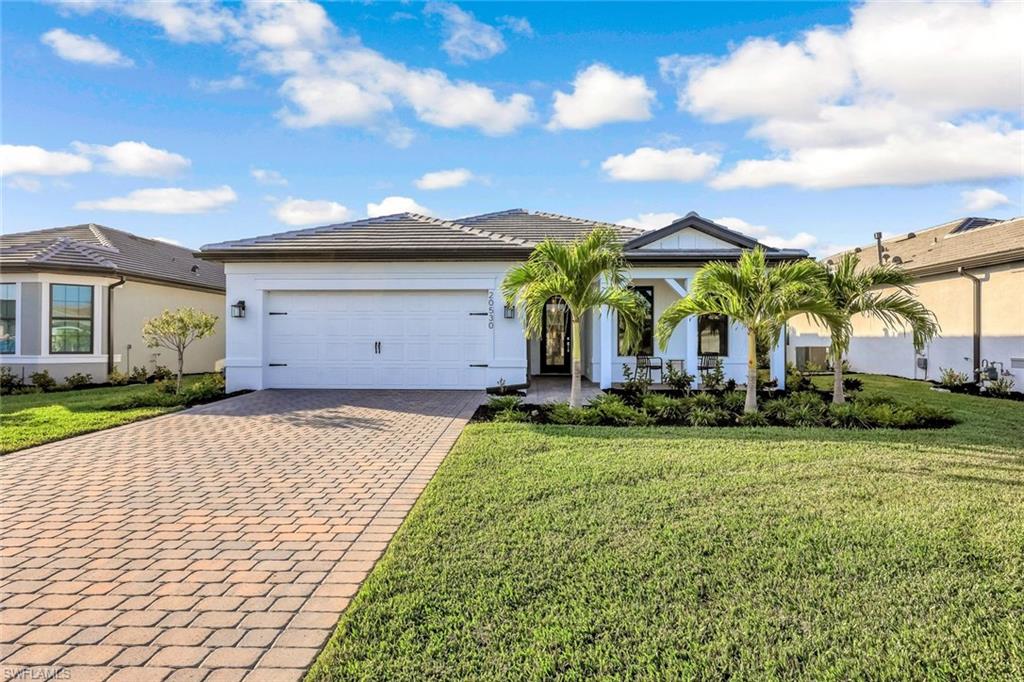 Ranch-style home with decorative driveway, a front yard, stucco siding, and a garage