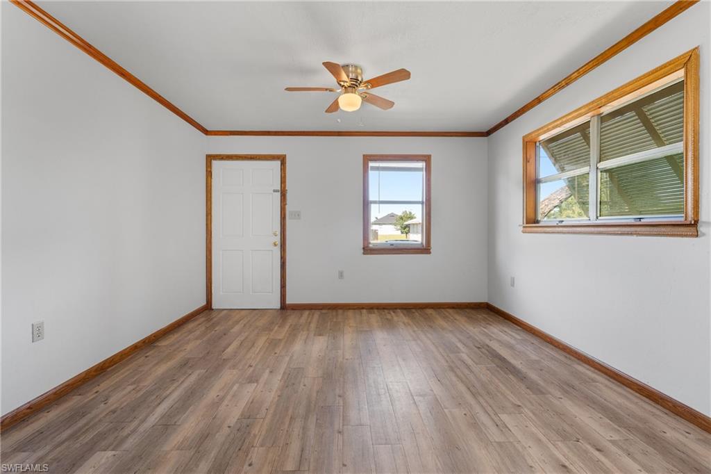 Unfurnished room with crown molding, light wood-style flooring, and a ceiling fan
