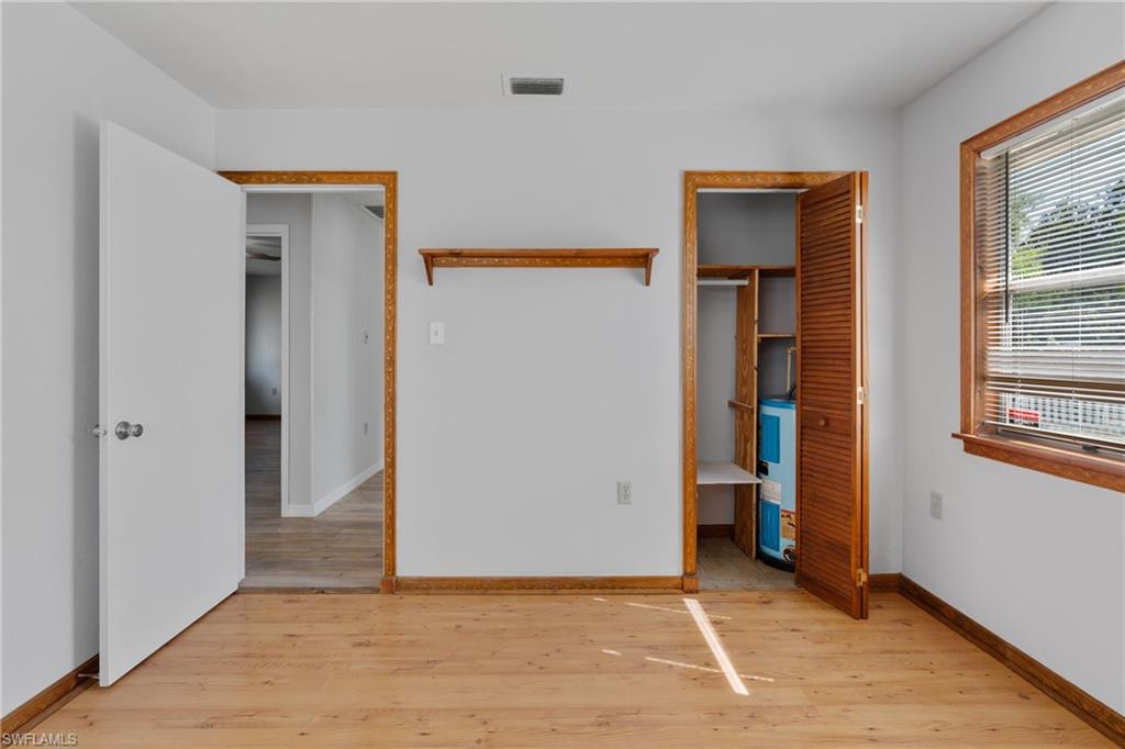 Unfurnished bedroom with a spacious closet, light wood-style flooring, and electric water heater