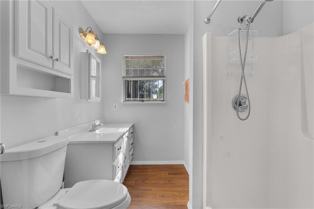 Bathroom featuring a shower stall, vanity, and wood finished floors