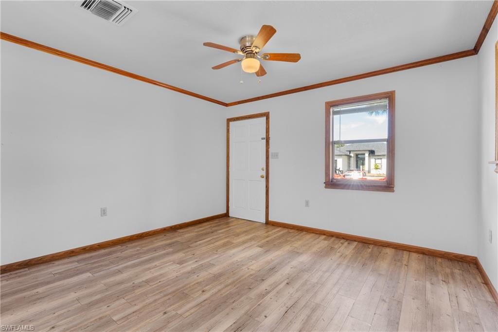 Empty room featuring crown molding, light wood-style flooring, and ceiling fan