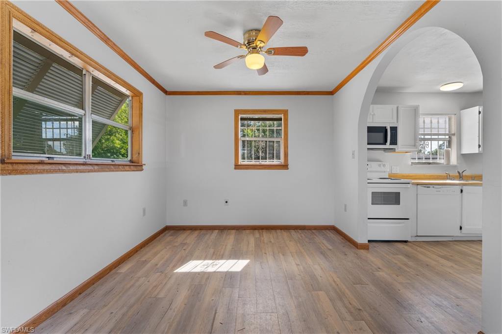 Kitchen featuring white cabinets, white appliances, ornamental molding, light wood-style floors, and light countertops