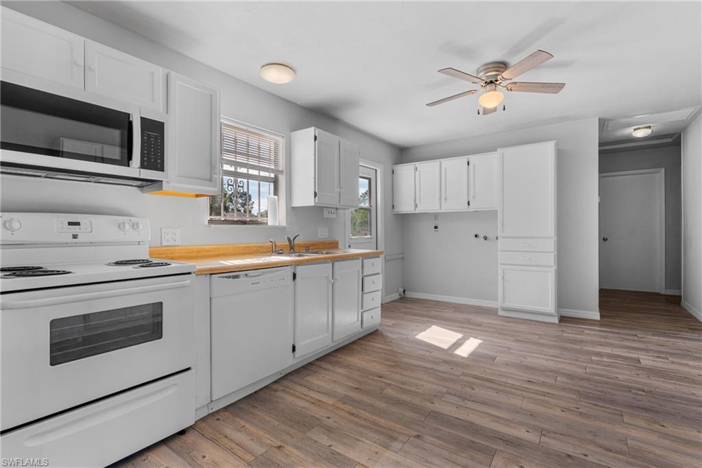 Kitchen featuring white appliances, white cabinetry, light wood-style flooring, and ceiling fan