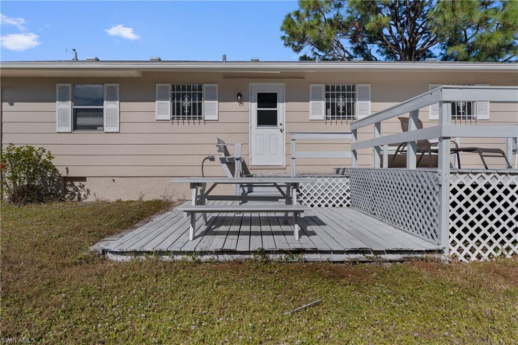 Rear view of house featuring a deck, a lawn, and crawl space