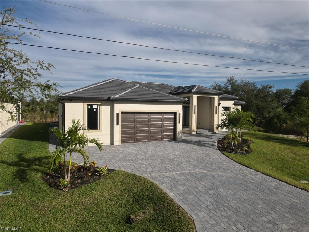 View of front of property featuring a front lawn, stucco siding, decorative driveway, and an attached garage