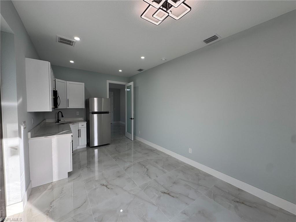Kitchen with white cabinetry, stainless steel appliances, light marble finish flooring, and recessed lighting