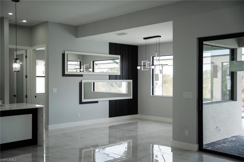 Unfurnished dining area with a chandelier and light marble finish flooring