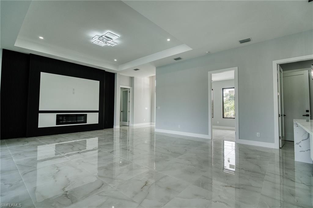 Spare room featuring light marble finish flooring, a raised ceiling, and recessed lighting