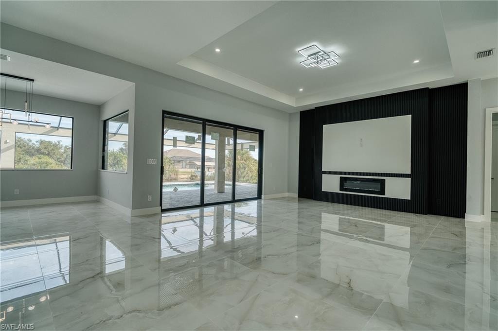 Empty room with light marble finish flooring and a raised ceiling