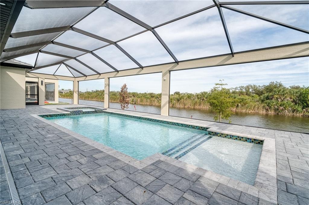 View of pool featuring a lanai, a sunroom, a pool with connected hot tub, a water view, and a patio