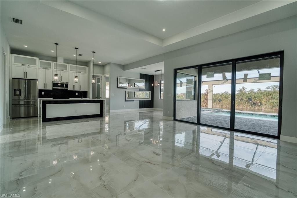 Unfurnished living room featuring healthy amount of natural light, light marble finish floors, and recessed lighting