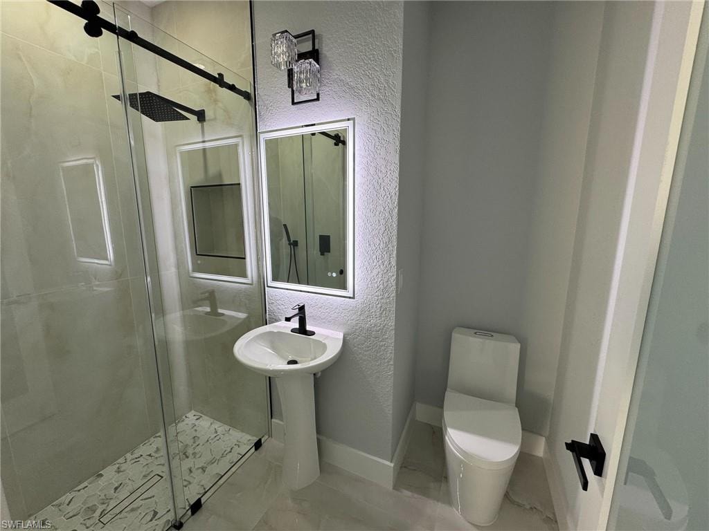 Full bathroom featuring a textured wall, a stall shower, and marble finish floors