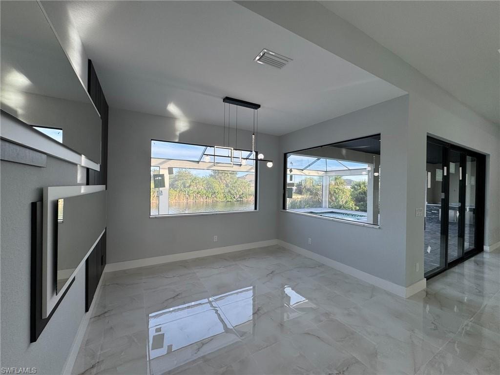 Unfurnished dining area featuring light marble finish flooring and baseboards