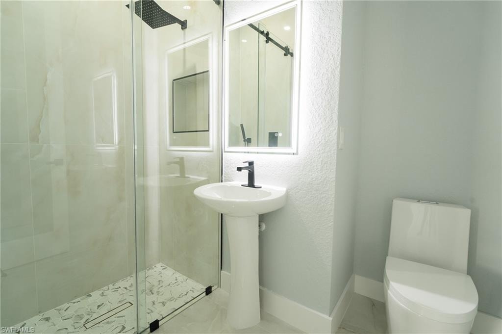 Bathroom with a stall shower, a textured wall, and tile patterned floors