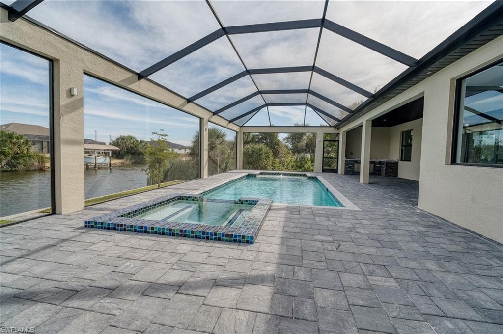 View of swimming pool featuring a sunroom, a pool with connected hot tub, a patio area, a water view, and a lanai