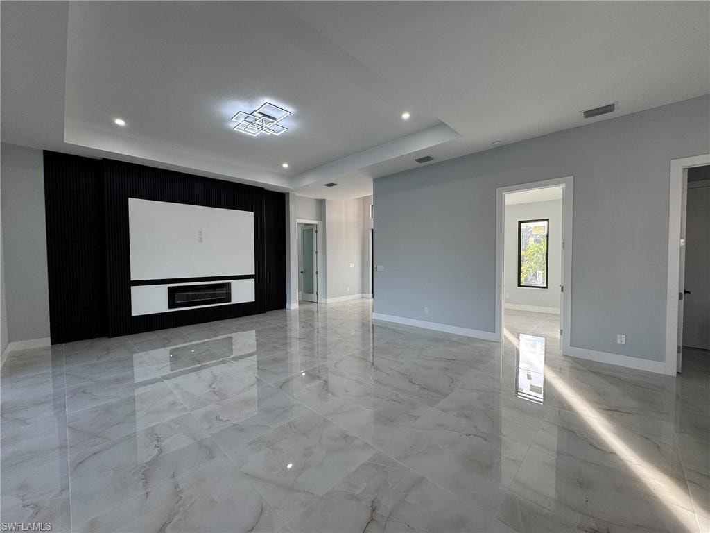Spare room with light marble finish flooring, a raised ceiling, and recessed lighting