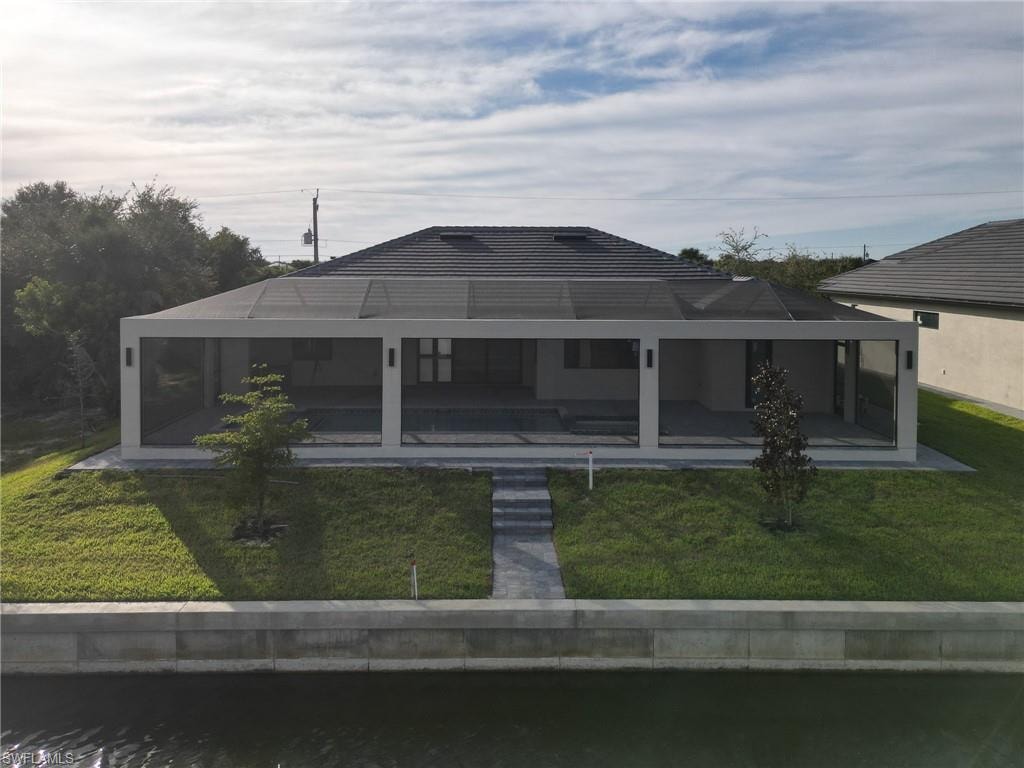 Rear view of house featuring a lanai, a yard, a sunroom, and an outdoor pool