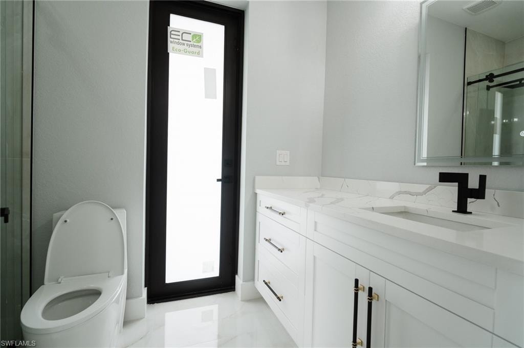Full bath featuring a shower stall, vanity, and light marble finish flooring