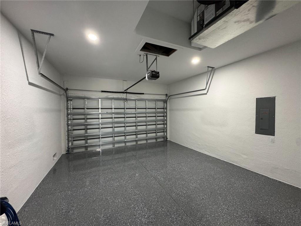 Garage featuring electric panel, a textured wall, and a garage door opener