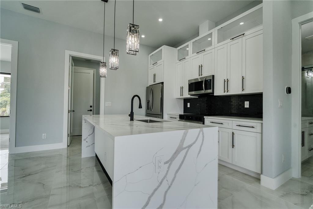 Kitchen with white cabinets, decorative light fixtures, light marble finish flooring, and recessed lighting