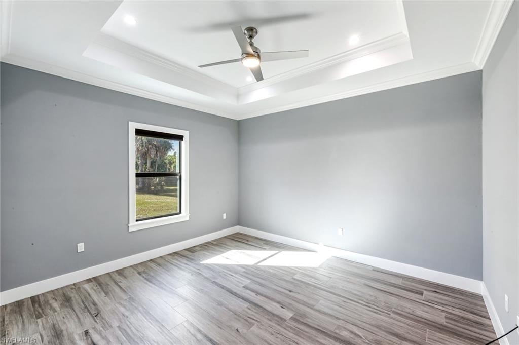 Spare room featuring a ceiling fan, light wood-type flooring, and ornamental molding