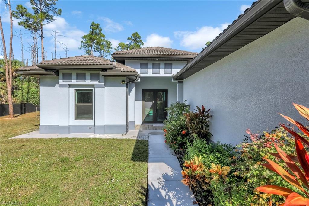 Property entrance with a yard and stucco siding