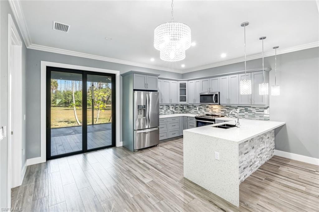 Kitchen featuring gray cabinetry, stainless steel appliances, ornamental molding, light stone countertops, and glass fronted cabinets