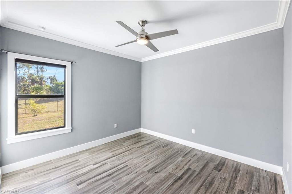 Spare room featuring ornamental molding, light wood finished floors, and a ceiling fan