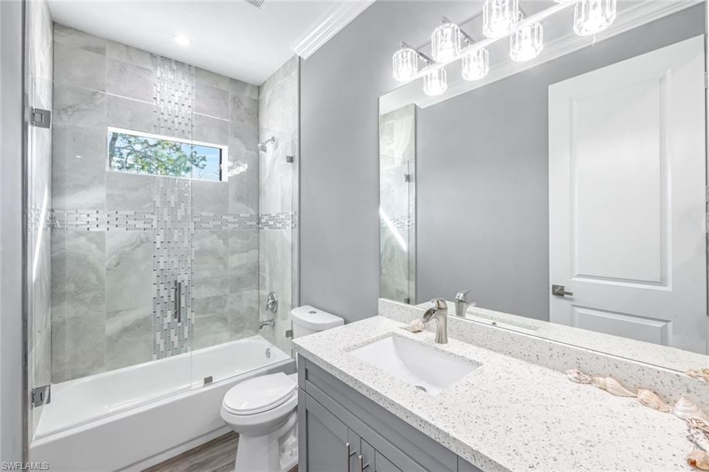 Full bathroom with vanity, shower / bath combination with glass door, recessed lighting, and ornamental molding