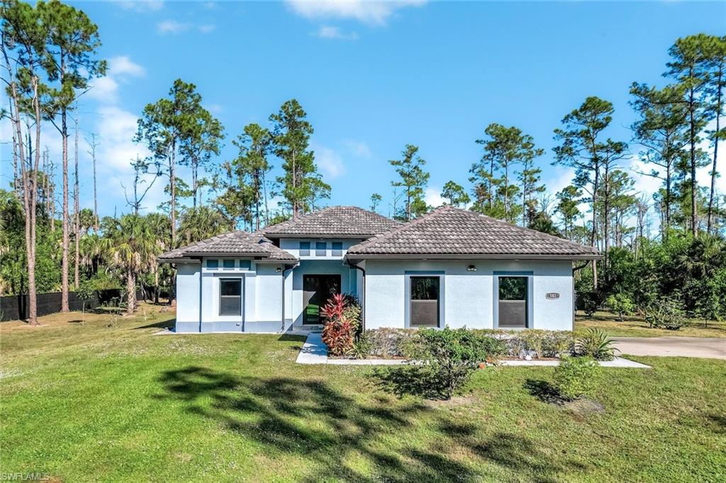 Back of house featuring a lawn, stucco siding, and a tile roof