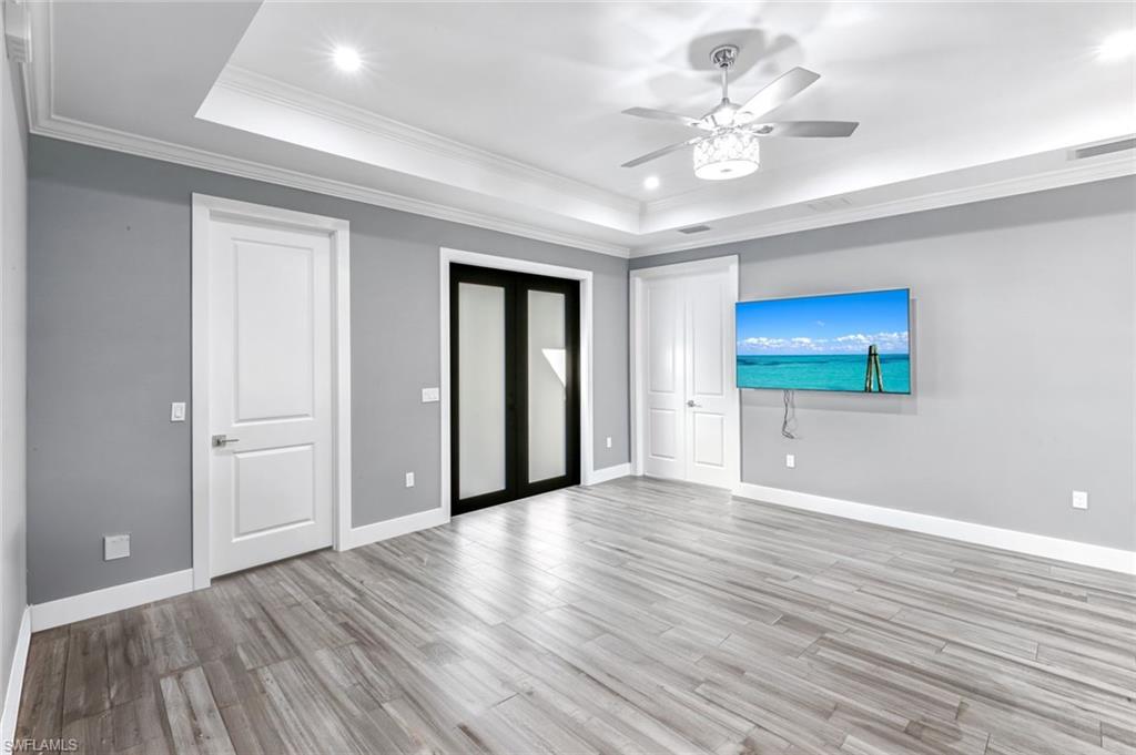 Unfurnished bedroom featuring crown molding, light wood-style flooring, recessed lighting, a ceiling fan, and a raised ceiling