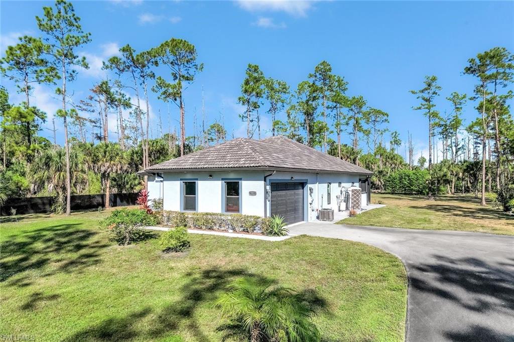 Single story home featuring a front lawn, asphalt driveway, stucco siding, an attached garage, and a tiled roof