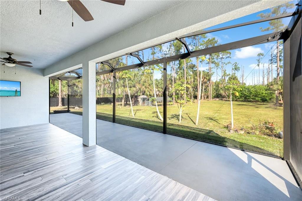 Unfurnished sunroom with a ceiling fan and a patio