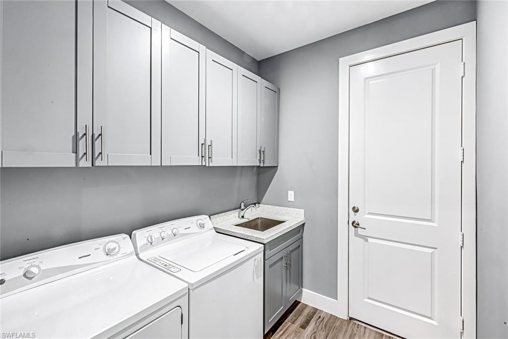 Laundry area with light wood-style flooring, independent washer and dryer, and cabinet space