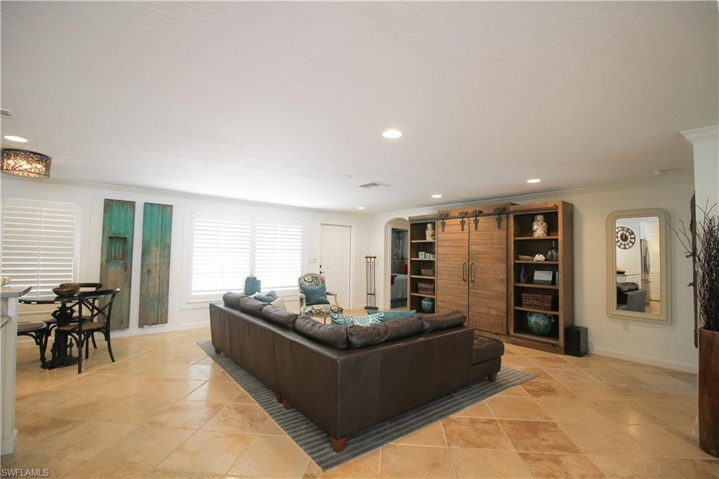 Living area featuring arched walkways, crown molding, and recessed lighting