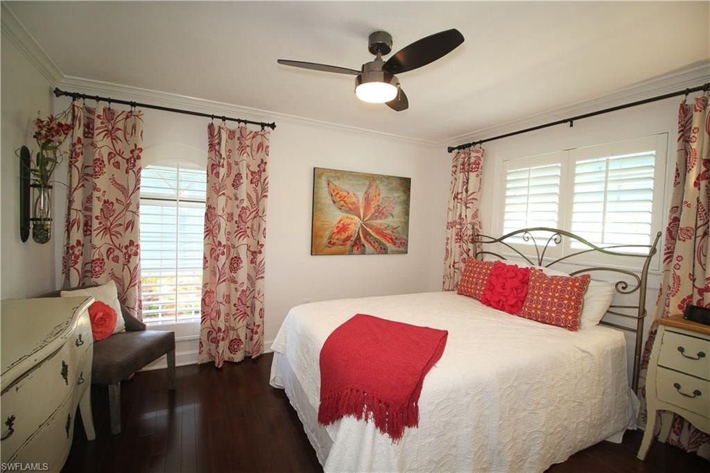 Bedroom featuring crown molding, dark wood-style flooring, ceiling fan, and multiple windows