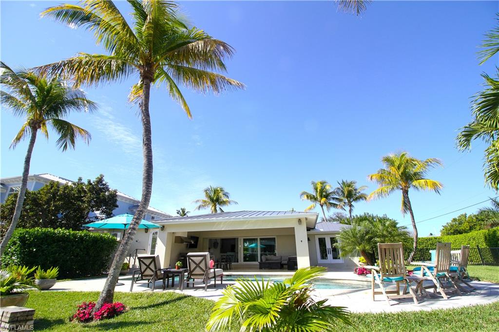 Back of property featuring a patio area, french doors, stucco siding, a metal roof, and a lawn