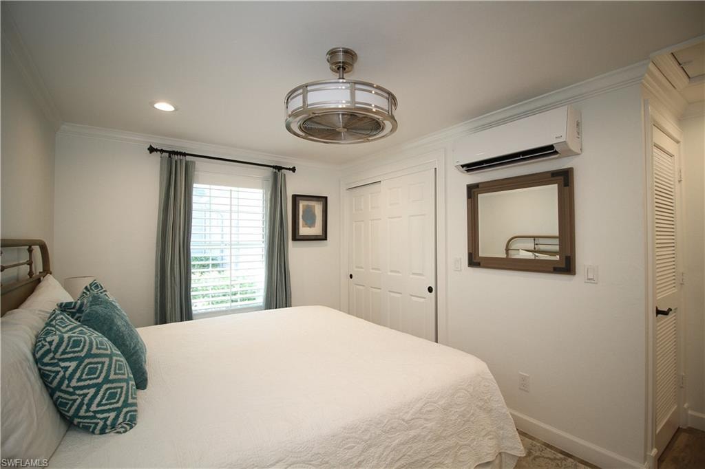 Bedroom with ornamental molding, a closet, a wall mounted air conditioner, and recessed lighting