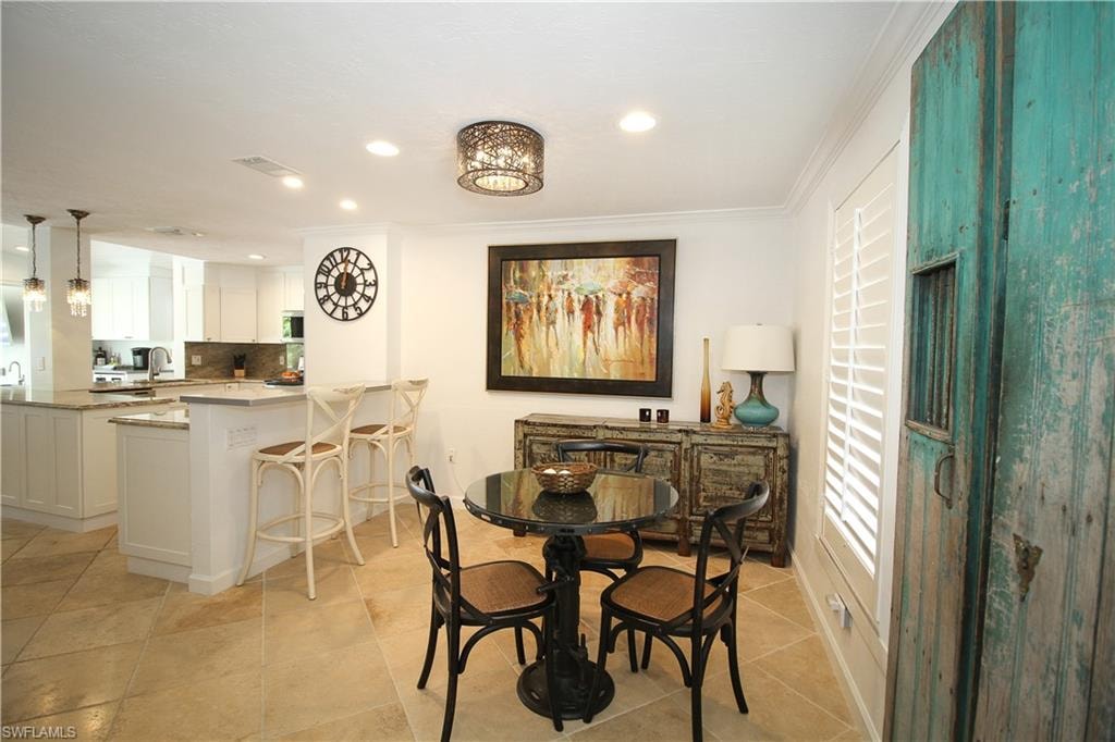Dining area with crown molding, recessed lighting, and light tile patterned floors