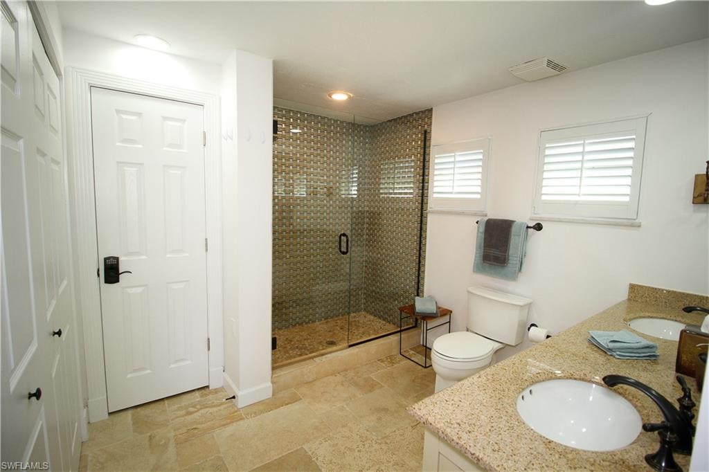 Bathroom with double vanity, stone tile flooring, a stall shower, and recessed lighting