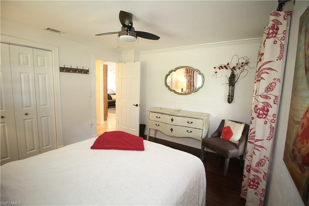 Bedroom with a closet, crown molding, a ceiling fan, and wood finished floors