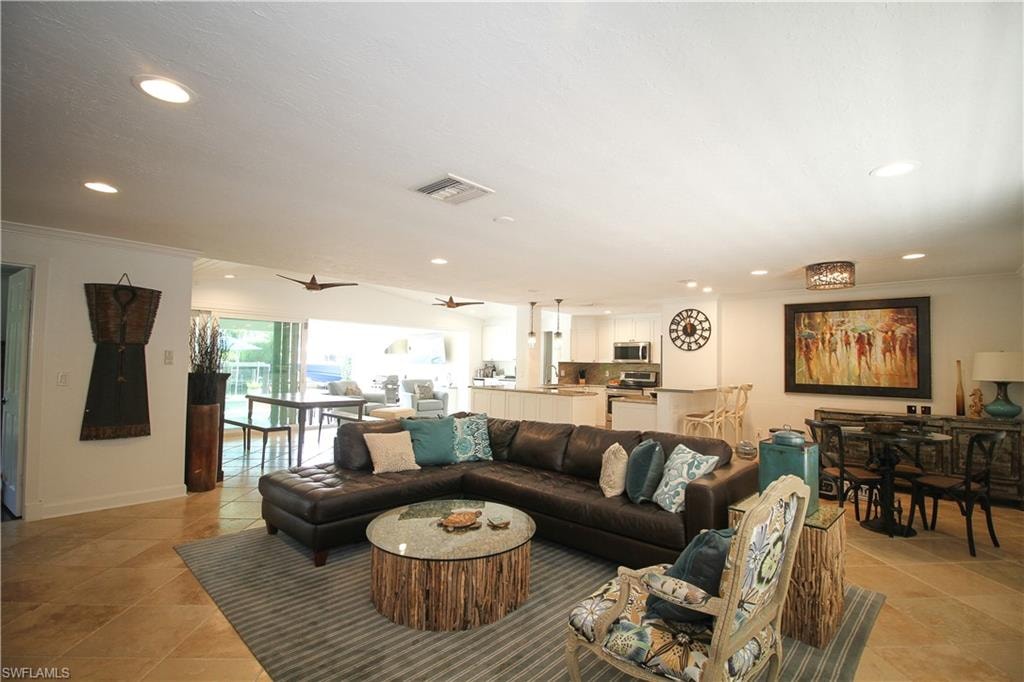 Living room with recessed lighting, crown molding, ceiling fan, and light tile patterned floors
