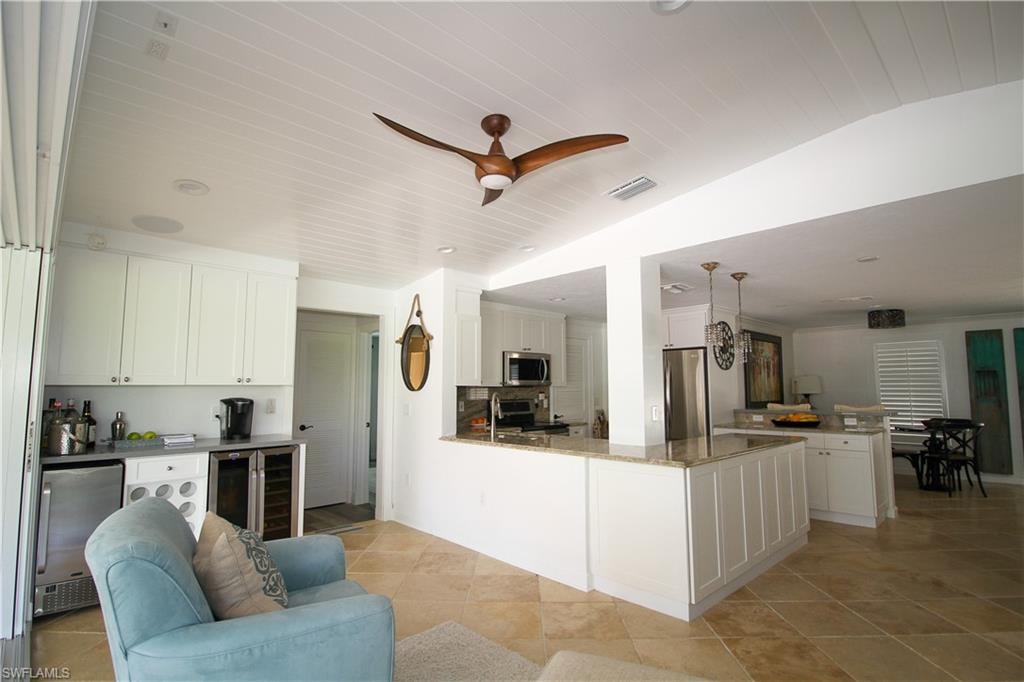 Kitchen featuring a peninsula, white cabinets, appliances with stainless steel finishes, dark stone countertops, and open floor plan