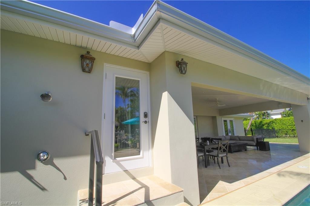 Doorway to property with outdoor lounge area, stucco siding, a patio area, ceiling fan, and outdoor dining area