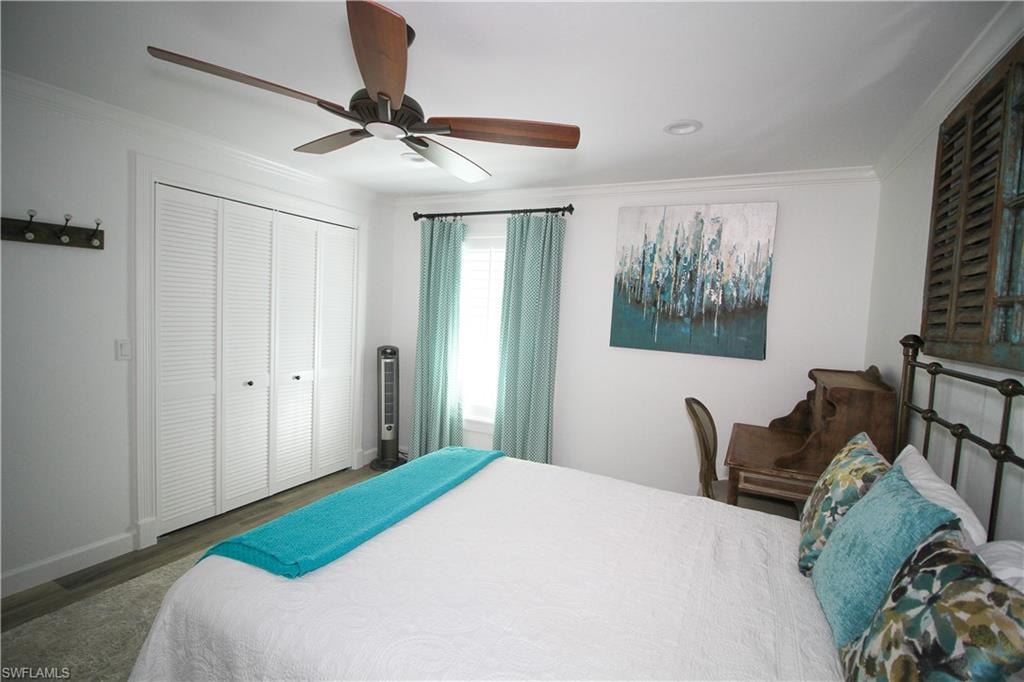 Bedroom with ceiling fan, crown molding, wood finished floors, and a closet