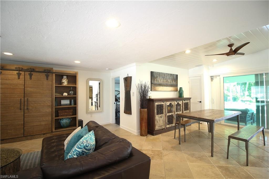 Living room with a ceiling fan, a barn door, recessed lighting, and light tile patterned flooring